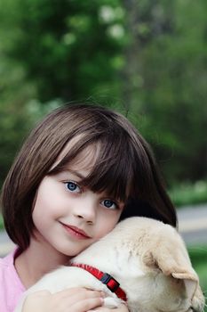 Little girl holding her puppy, an English Cream Labrador Golden retriever mix.