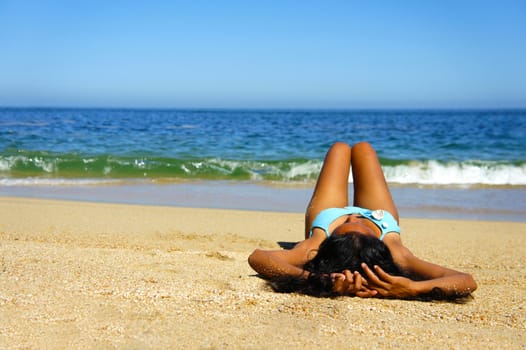 Young woman laying on beach sun tanning.