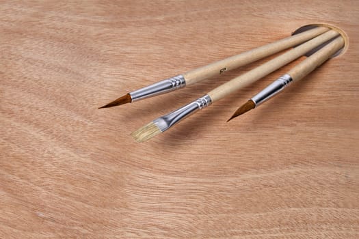 Artist paint brushes on clean wooden palette background