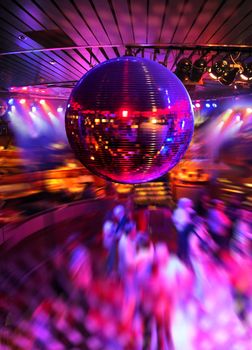 People dancing under colorful lights of disco mirror ball