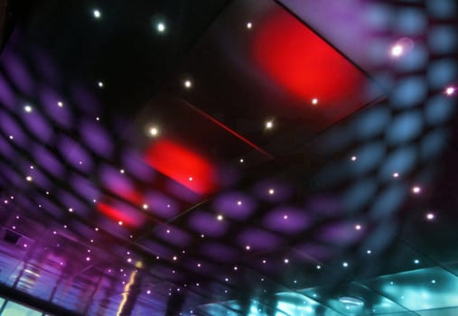 Colorful disco light spots in reflective nightclub ceiling