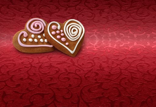 Two heart shape cookies on Christmas red brocade fabric