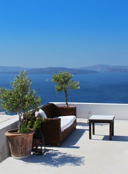 Vacation terrace with sofa and table above blue sea