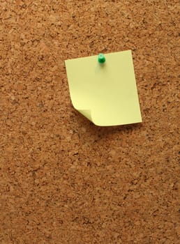 Empty yellow note paper on cork board background