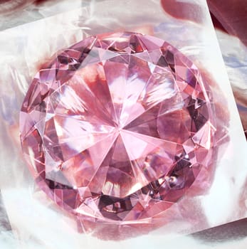 Pink gemstone diamond shining on reflective background