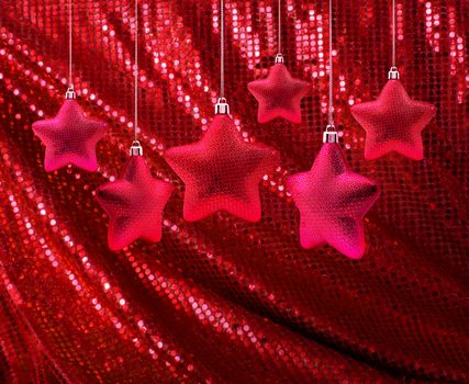 Red Christmas decoration stars hanging on red glitter canvas
