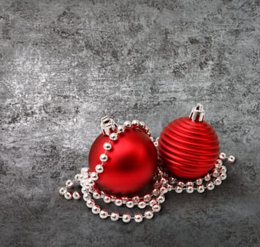 Red christmas decoration glass balls and pearls on textured silver background