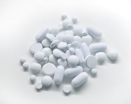 Pile of white medicine pills on light background