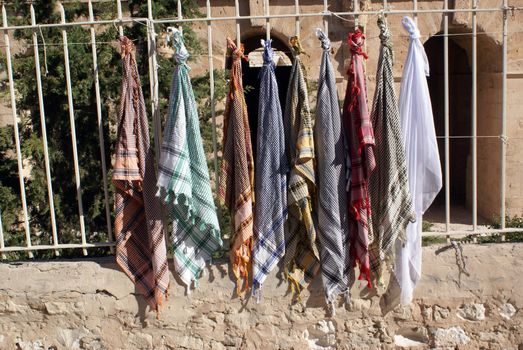 Cheap arabic scarfs for tourists near the wall of roman theater in El-Jem, Tunisia               