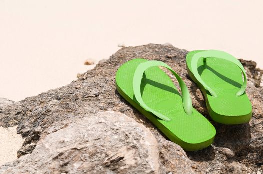 green flip flops on a rock at the beach (copy-space available)