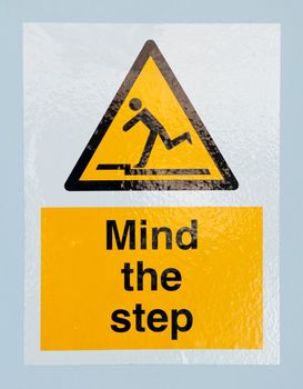 mind the step caution sign on a blue wall background