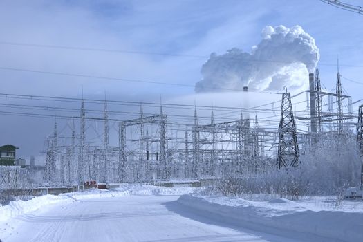Powerful power station costing in an environment of snowdrifts on a background of the blue sky