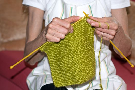 woman sitting on couch and knitting wool