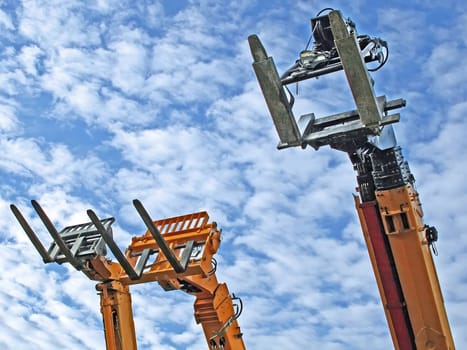 three fork-lift trucks, pointing towards the sky, waiting for their use