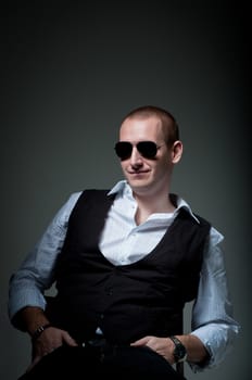 Young man sitting in chair smiling in sunglasses