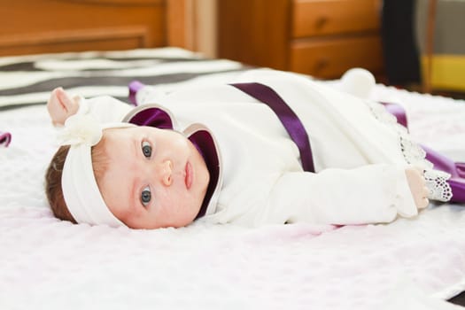 close-up portrait of baby girl  lying on bed and looking at camera