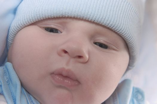 nice kid in a blue cap with a thoughtful kind looks downwards