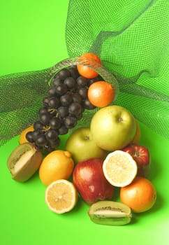 rich assortment of fruit consisting of apples, citron, grapes, kiwi on a green background