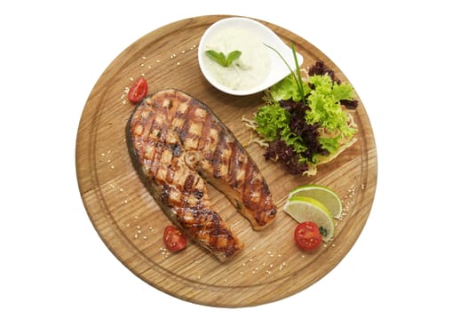 Salmon steak with herbs and lemon on a wooden platter