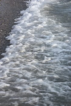 Sea foam formed from waves rolling on coast