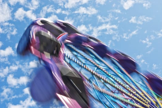 Popular attraction in park - a Ferris wheel on a background of the cloudy blue sky