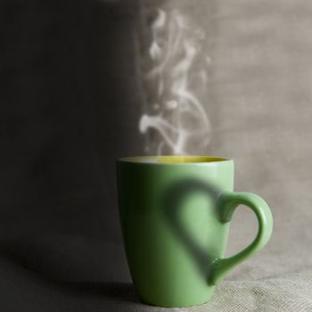 A green mug with hot coffee and a heart.