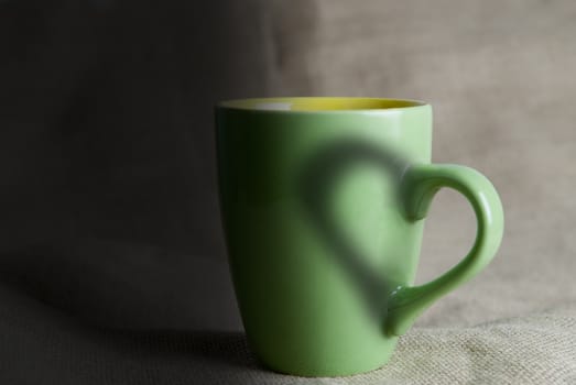 A green mug with hot coffee and a heart.