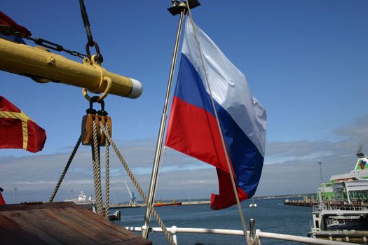 The Russian flag and sailing vessel calling in port of a city of Tallinn, Estonia