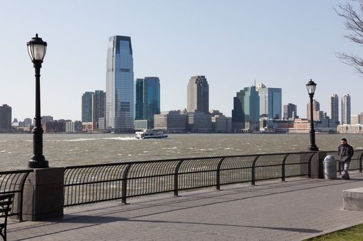New YORK, USA - MARCH 26: Man walking windy NY riverfront on March 26, 2012. Goldman Sachs Tower rises 548 feet.