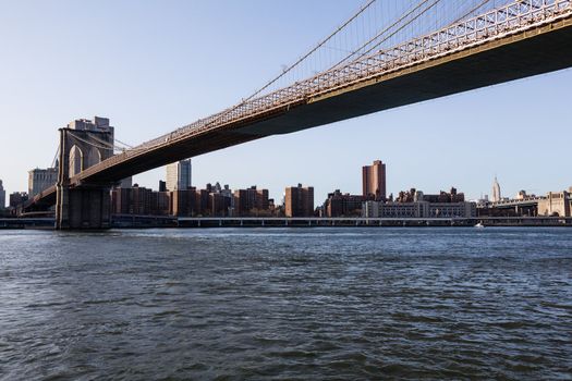 Empire State Tower visible under span of Brooklyn bridge in NY