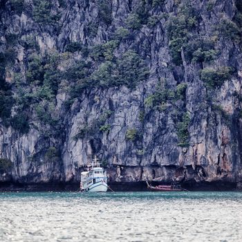 rocky shore and tour ferry in Andaman Sea, Thailand