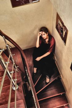 young beautiful lady sitting on stairway in luxury interior