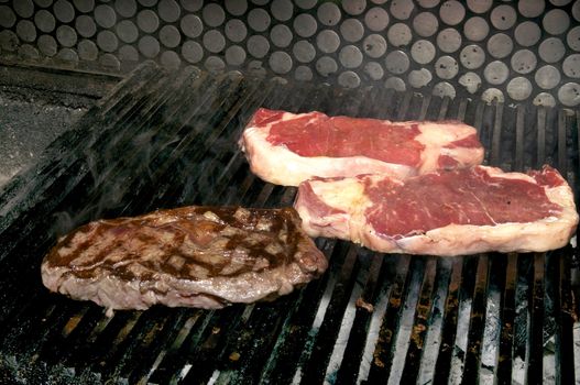 cooking beef steaks on the grill in the restaurant