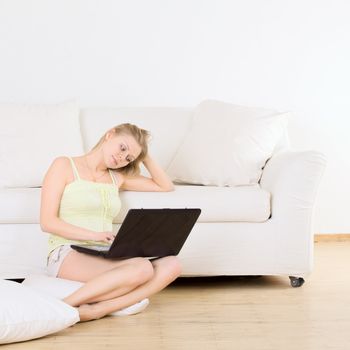charming woman sitting near sofa with laptop