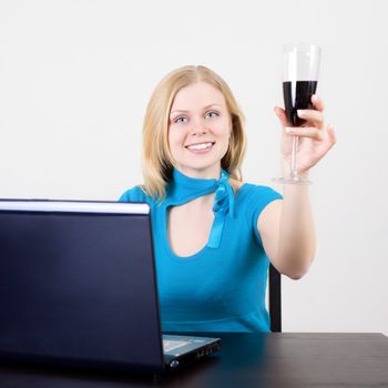 business woman celebrating her success with wine in front of her computer