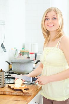 cute young woman cutting onion at kitchen