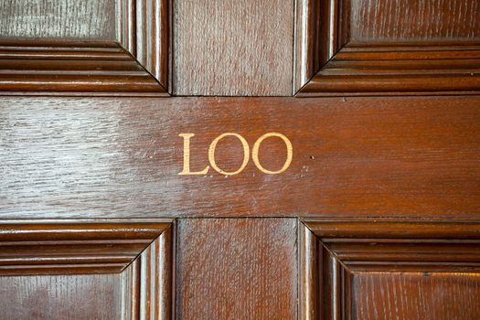 Door to restroom with word Loo painted onto wooden door
