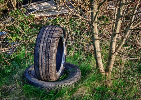 Dumped car tyres abandoned in overgrown field