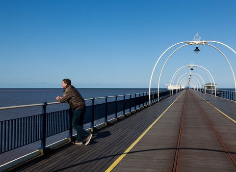 Single caucasian male looking at sea from pier in Southport England