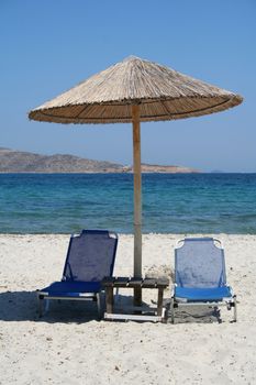 Greece. Kos island. Tigaki beach.Two chairs and umbrella on the white sand beach