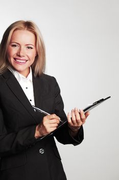 business woman writing in notebook on a gray background