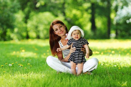 Happy mother and daughter on the green grass