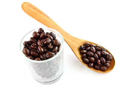 Coffee beans in a glass with wooden spoon on white background