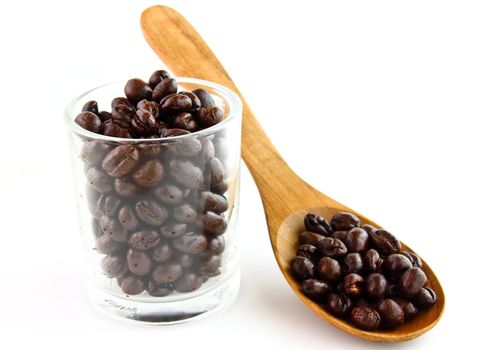 Coffee beans in a glass with wooden spoon on white background