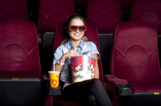 young woman sitting alone in the cinema and watching a movie