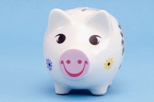 Isolated white ceramic piggy box money-box with smiles and flowers decors on white background. Saving money for black day. Nest-egg.