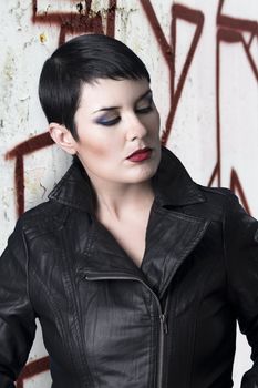 Sexy brunette young woman in a leather jacket over urban background