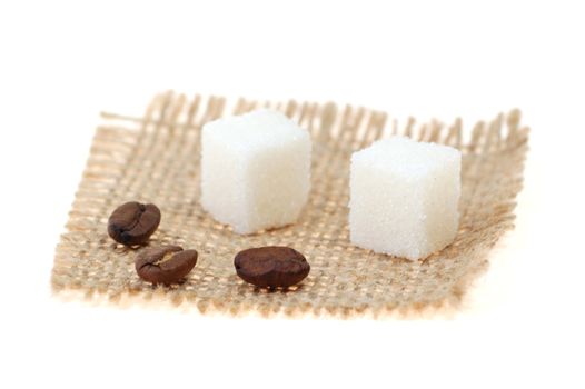 Coffee beans and lump sugar on sackcloth