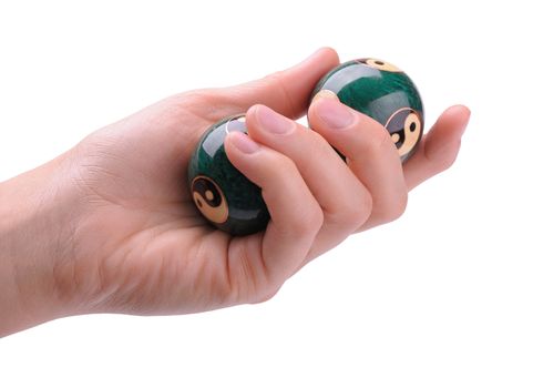 Green Chinese balls for relaxation in woman's hand on white background