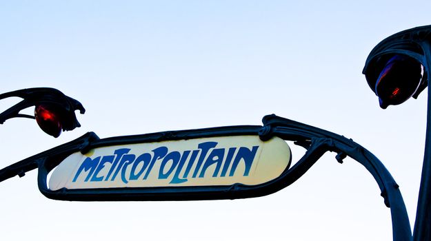 Traditional entrance sign of metro station in Paris. Clean sky in background, copy space